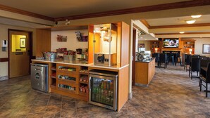 A hotel lobby with a self-service beverage station, a small refrigerator, and a television in the background. - Canalta Hotel Provost (Provost)