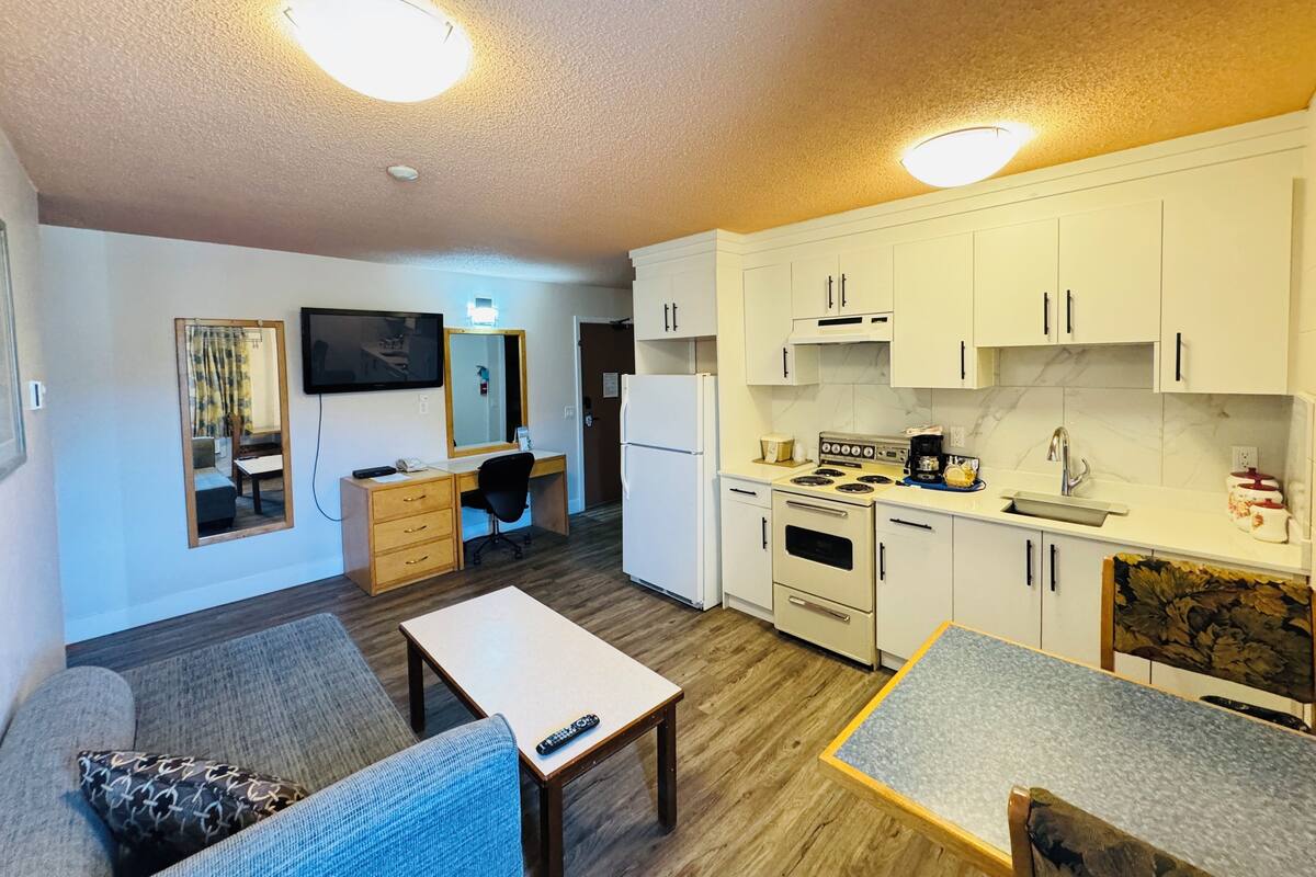 A compact living space with a kitchenette, a dining area, and a seating area with a sofa and a small table.