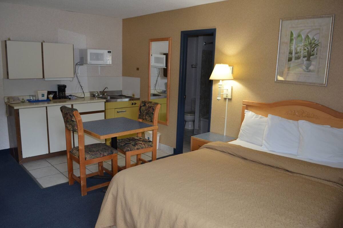 A hotel room with a bed, a desk with a chair, a microwave, and a small bathroom.