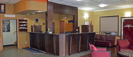 A reception area with a wooden reception desk, a clock, a red couch, and a sign indicating room numbers on the 2nd floor.