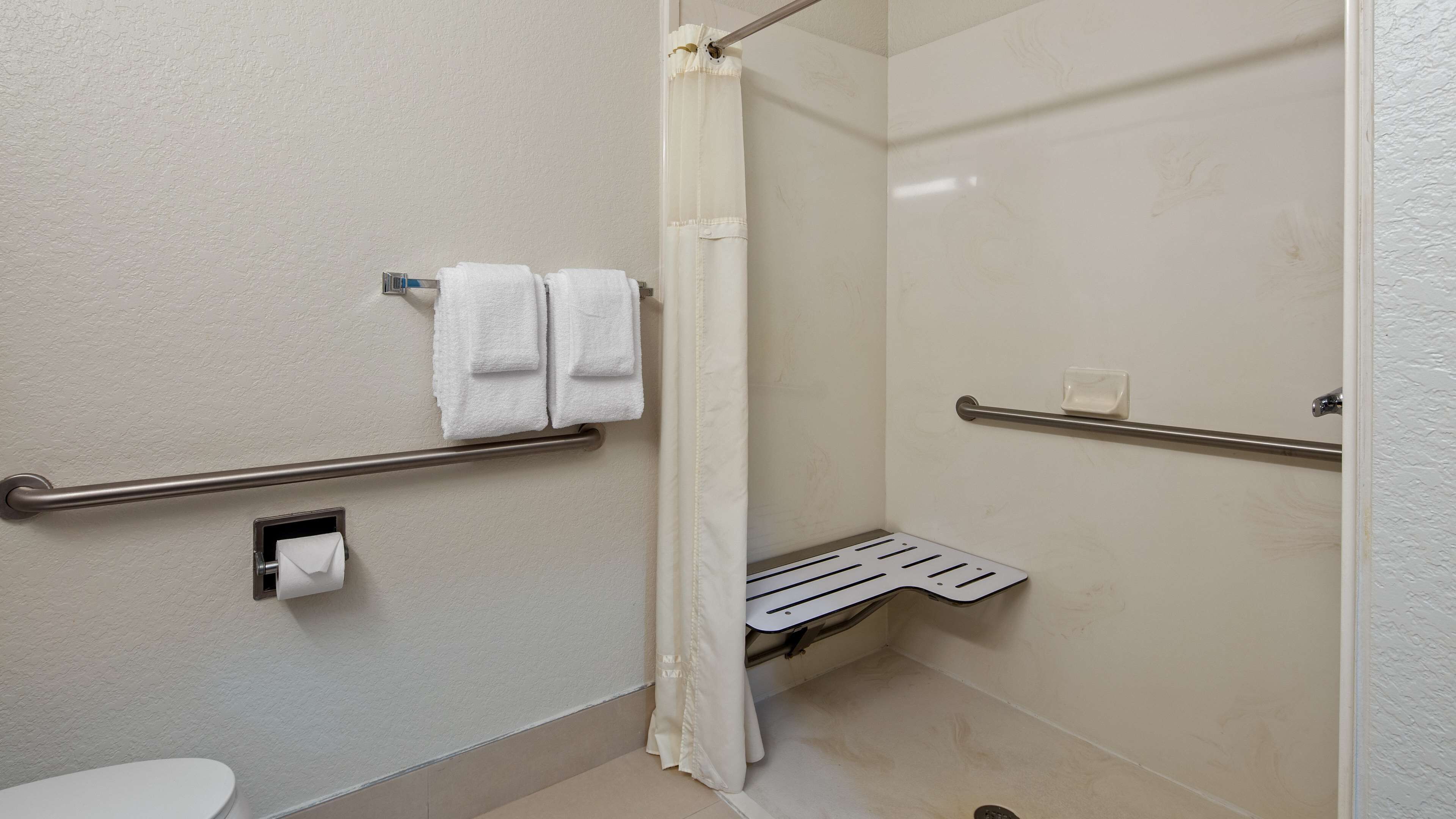 A bathroom with a toilet, a shower with a glass door, and a towel rack with two towels.