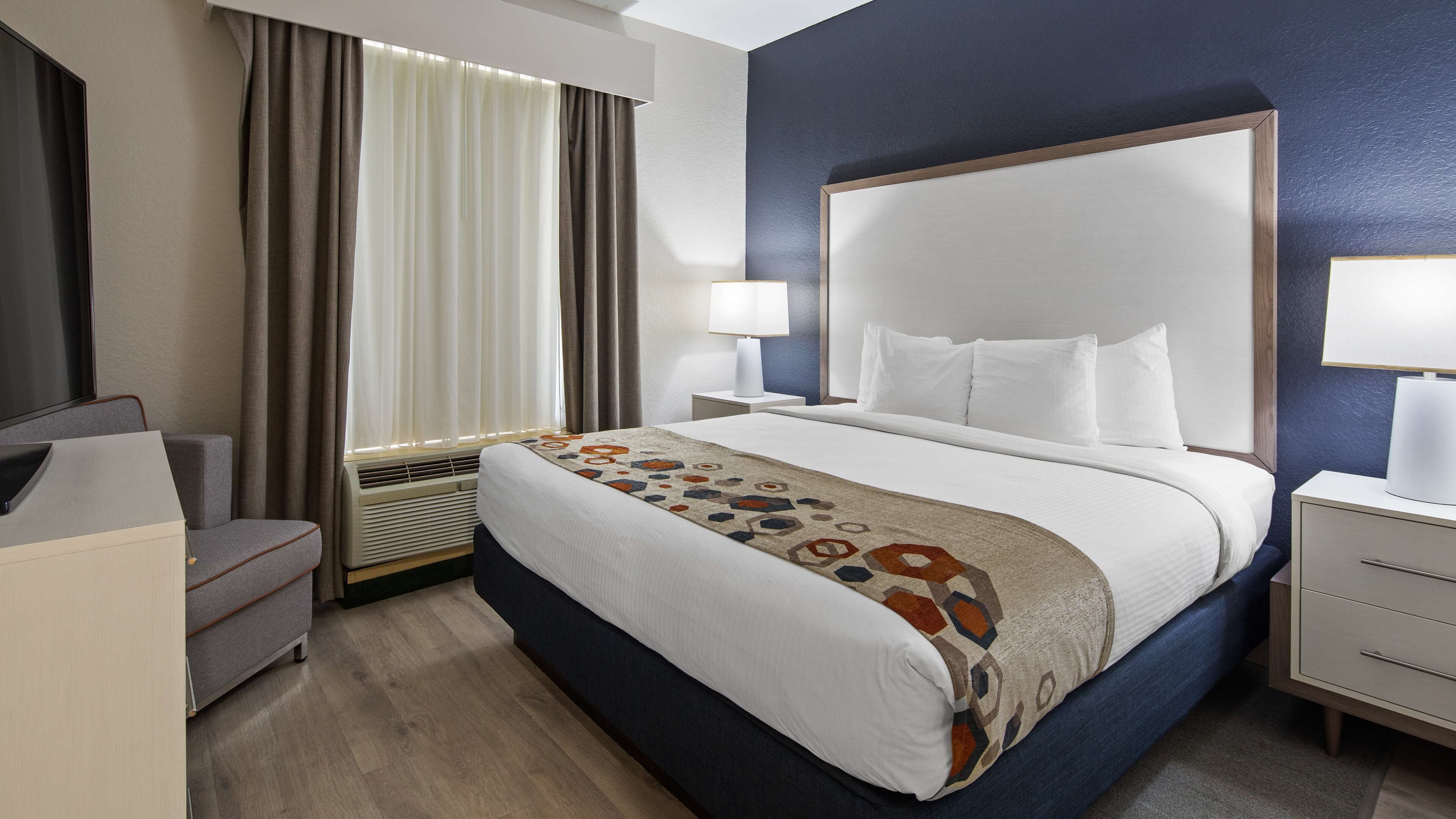 Une chambre d’hôtel avec un grand lit, des tables de chevet, un bureau et une télévision.