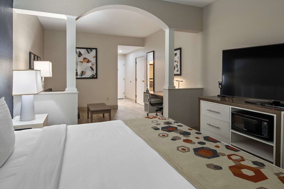 A hotel room with a large bed, a desk with a computer, a TV, and a microwave.