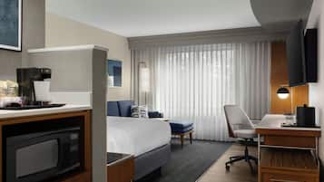 A hotel room with a bed, desk, chair, and a television.