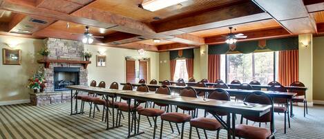 Un salón de conferencias con largas mesas, sillas, una chimenea y una alfombra estampada.