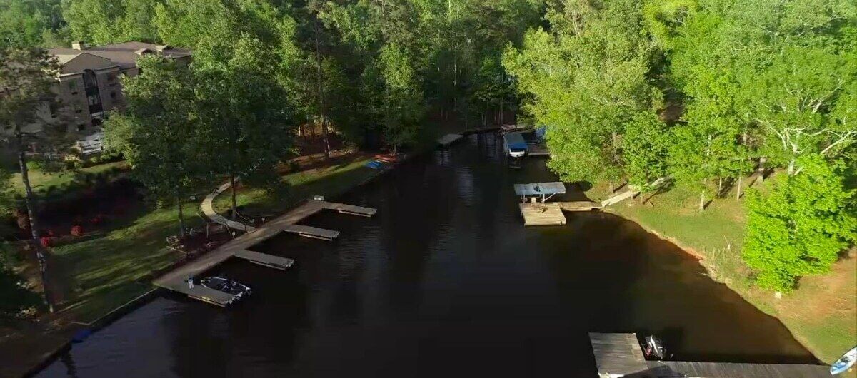 Un río con muelles, rodeado de árboles y un edificio.