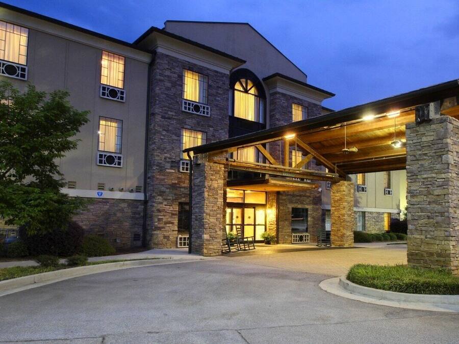 A hotel entrance with a covered walkway, stone pillars, and a well-lit facade.