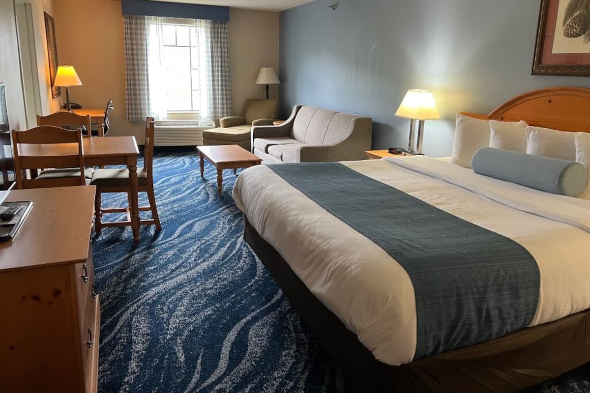 Ein Hotelzimmer mit einem großen Bett, einem Schreibtisch mit Stuhl, einer Couch und einer Lampe.