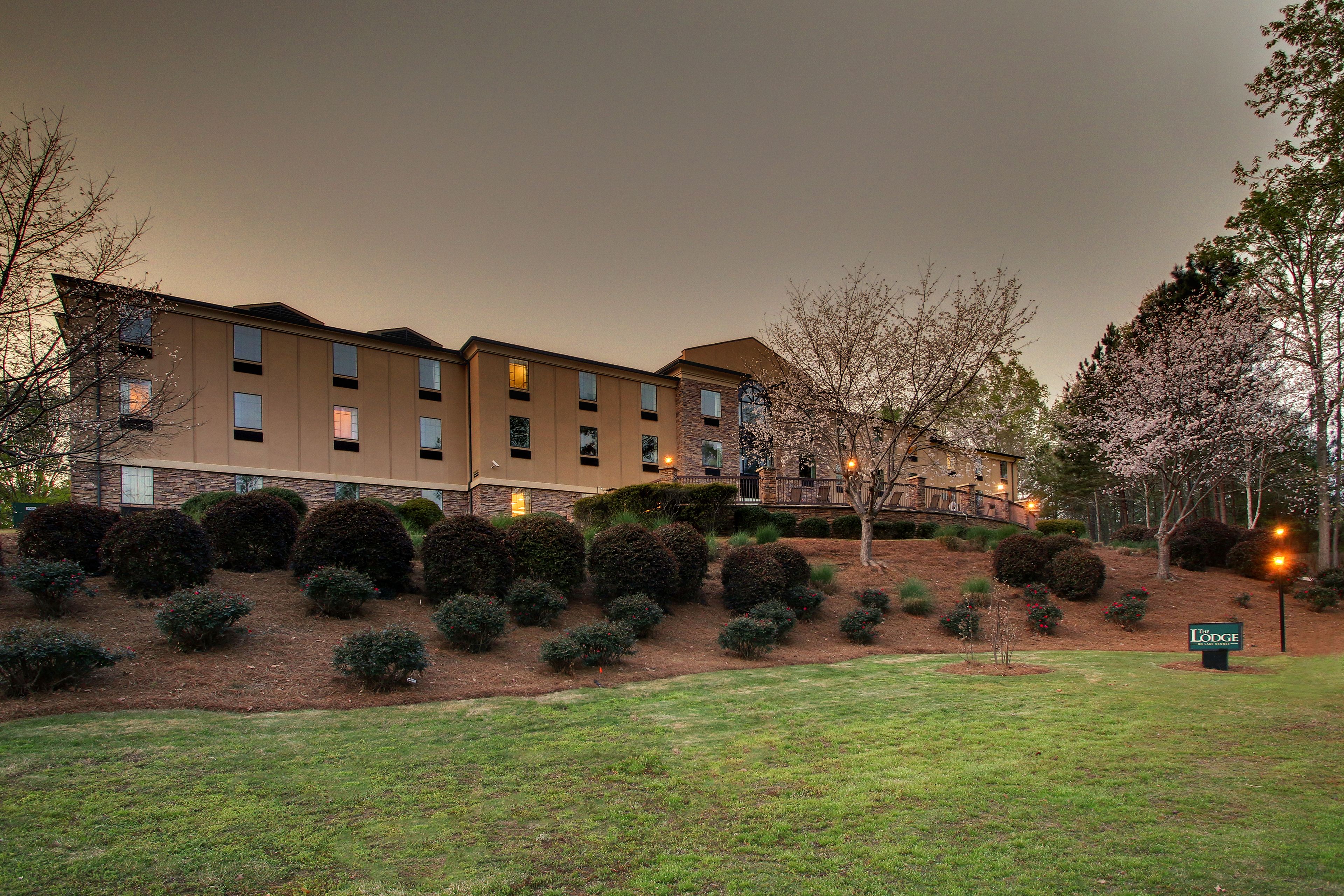 A multi-story hotel with a landscaped front yard, including trimmed bushes and a sign that reads "Lodge."