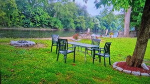 Un parc avec une table de pique-nique et des chaises, entouré d’une végétation luxuriante et d’arbres.