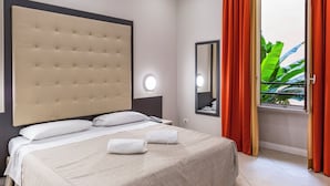 A hotel room with a large bed, a headboard, a bedside table with a lamp, a mirror, and a window with curtains. - Hotel Demó (Milan)