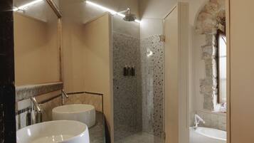 A bathroom with a marble countertop, two sinks, a shower, and a bathtub.