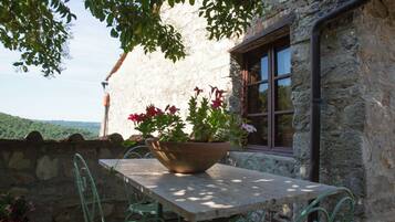 A stone building with a table and chairs, a window, and a view of the landscape.