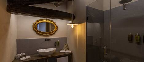 A bathroom with a wooden vanity, a large mirror, a glass shower enclosure, and a towel rack.