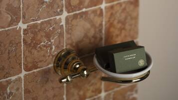 A bathroom with a tiled wall, a mounted television, and two bottles of liquid soap.