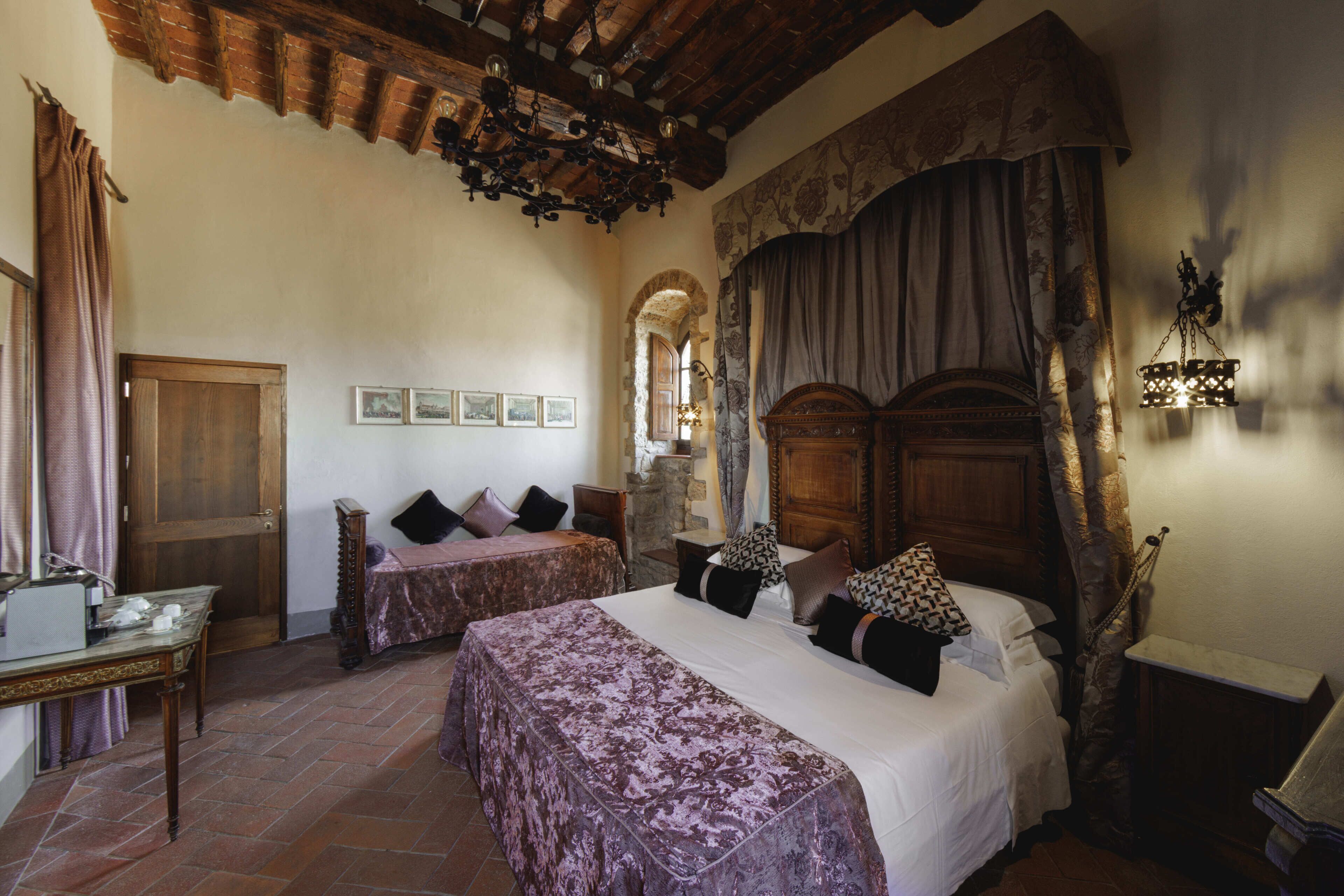 A traditional room with a bed, a wooden desk, and a stone wall.