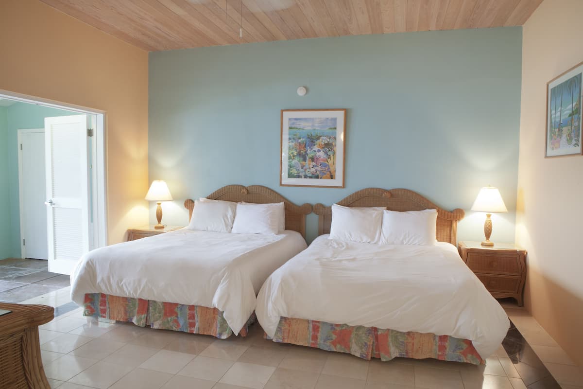 Una habitación con dos camas, una puerta y un cuadro en la pared.