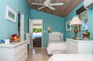 A bedroom with a bed, a dresser, a ceiling fan, and a view of the outdoors. - Cape Santa Maria Beach Resort (Galliot Cay)