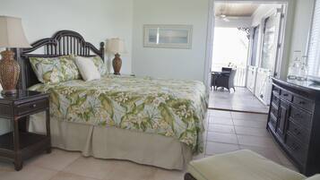 A bedroom with a bed, bedside tables, a dresser, and a balcony with a table and chairs.