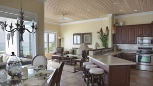 A spacious kitchen with a large island, modern appliances, and a dining area with a glass table and chairs. - Cape Santa Maria Beach Resort (Galliot Cay)