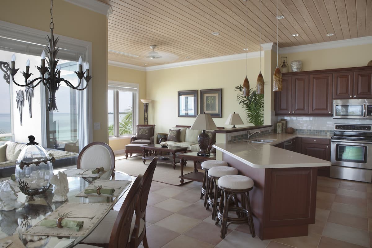 Una cocina amplia con una isla grande, electrodomésticos modernos y un comedor con mesa y sillas de vidrio.