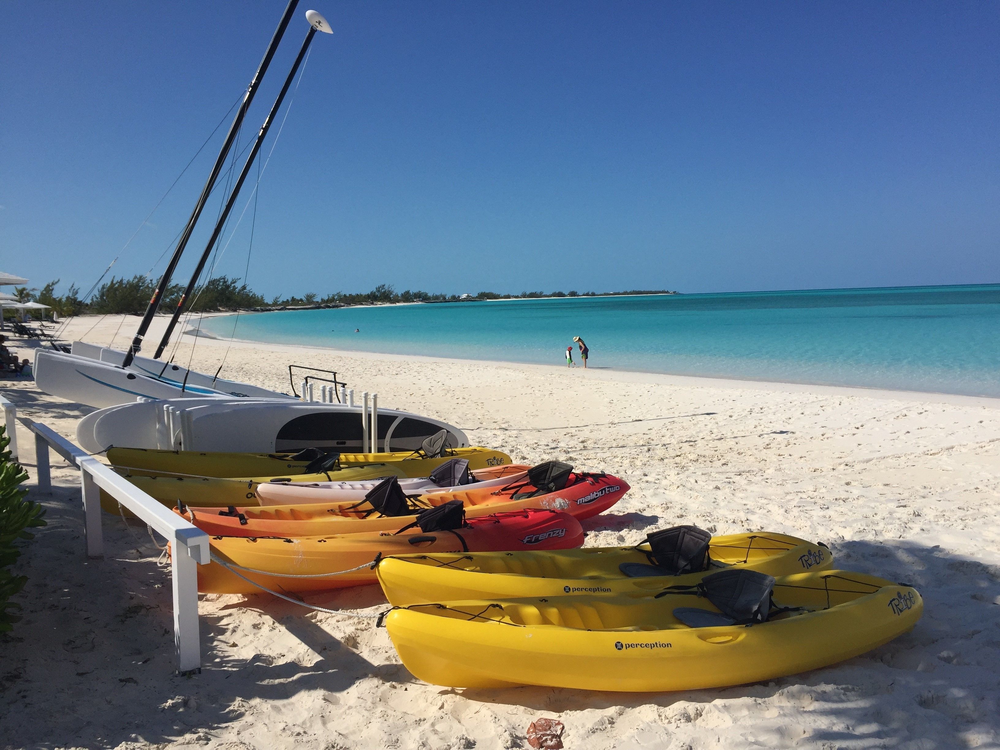 A beach with kayaks and a sailboat.