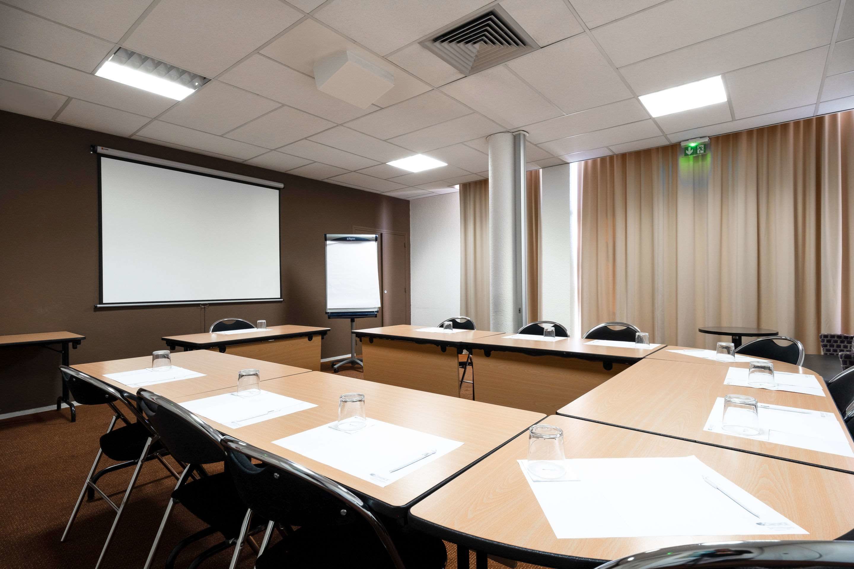 A conference room with a large table, chairs, a projector screen, and a whiteboard.