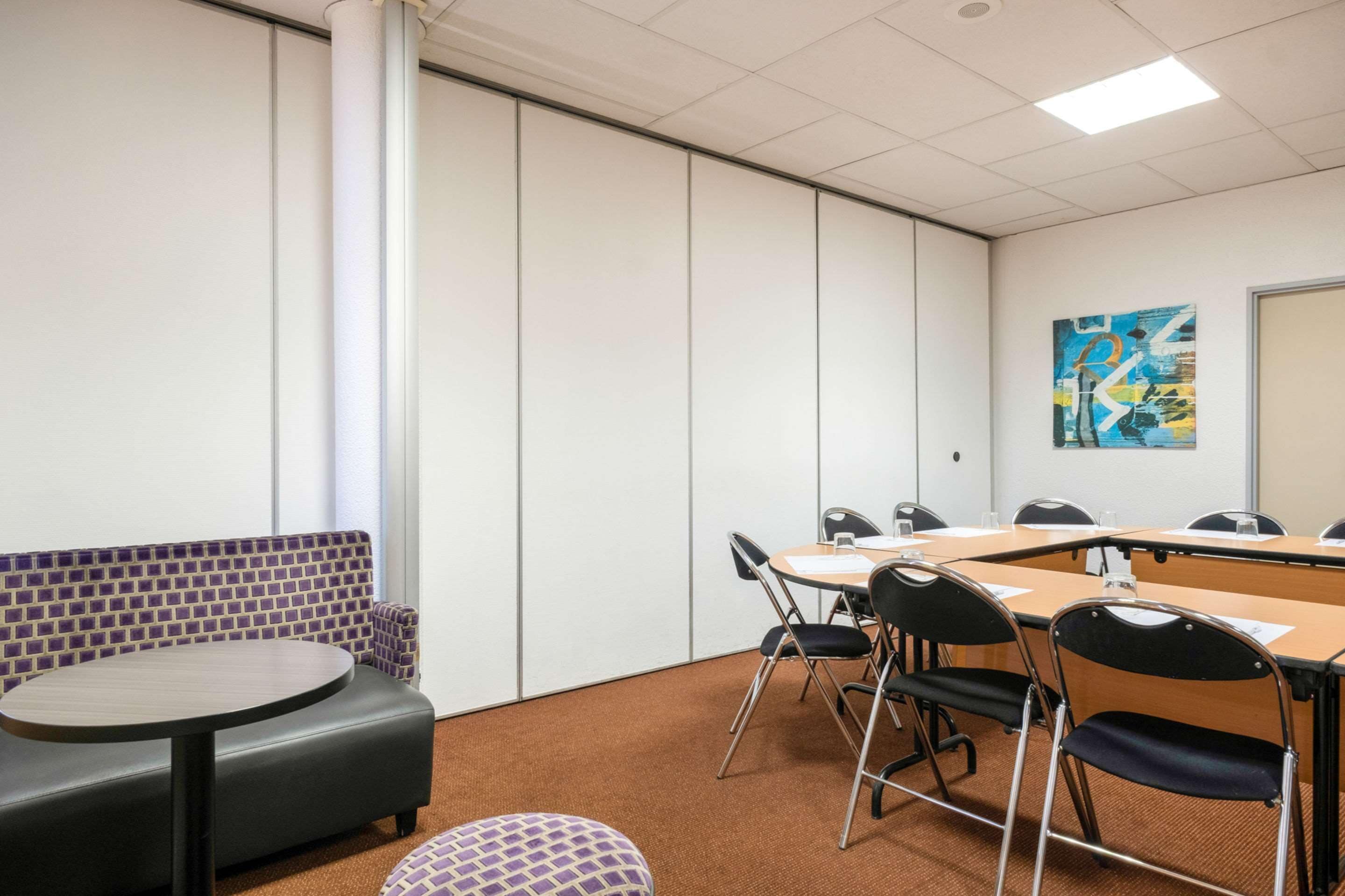 Een vergaderruimte met een lange tafel, stoelen, een bank en een kleine ronde tafel.