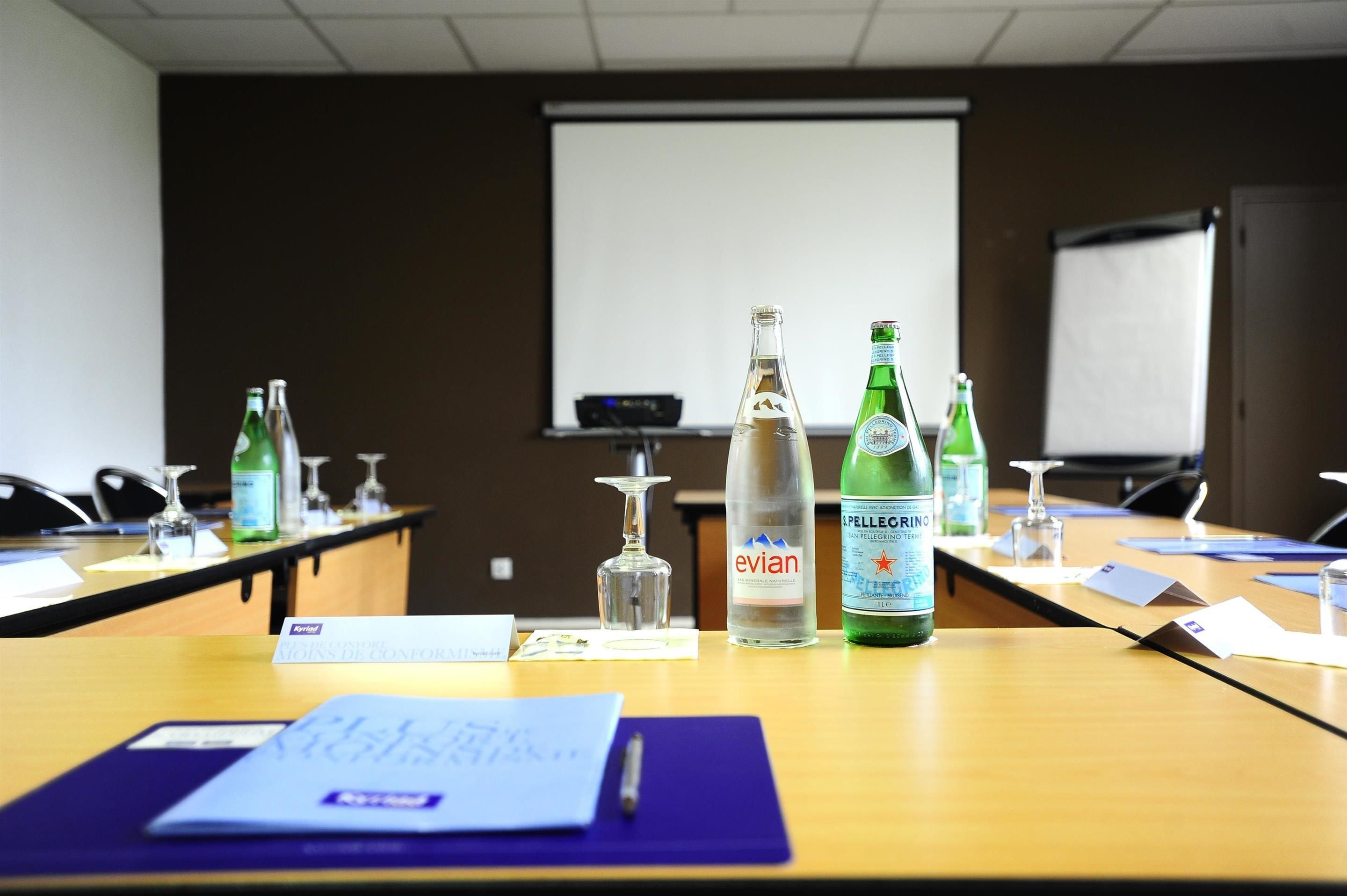 A conference room with a long table, nameplates, and various bottles of water and alcohol.