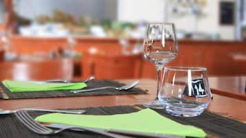 Een eettafel met bestek en twee glazen, met een vage achtergrond die een restaurant of eetgedeelte doet vermoeden.