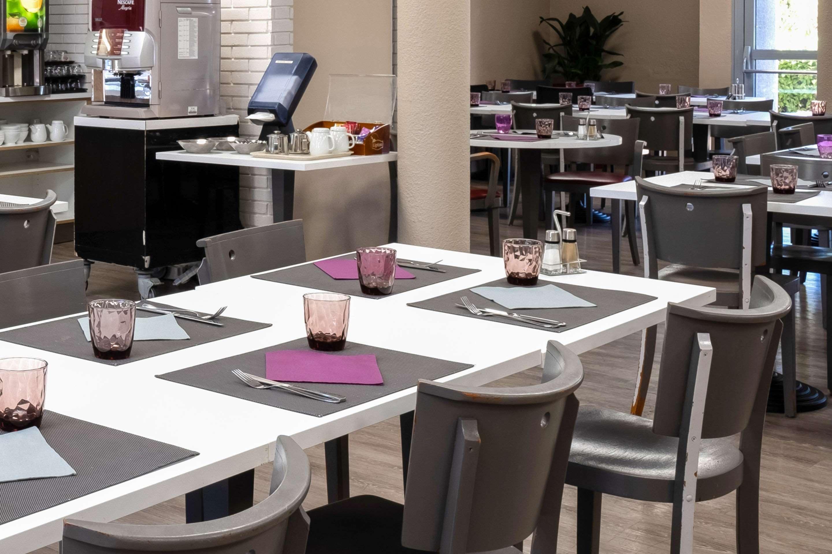 A restaurant with multiple tables, each set with cutlery, napkins, and glasses.