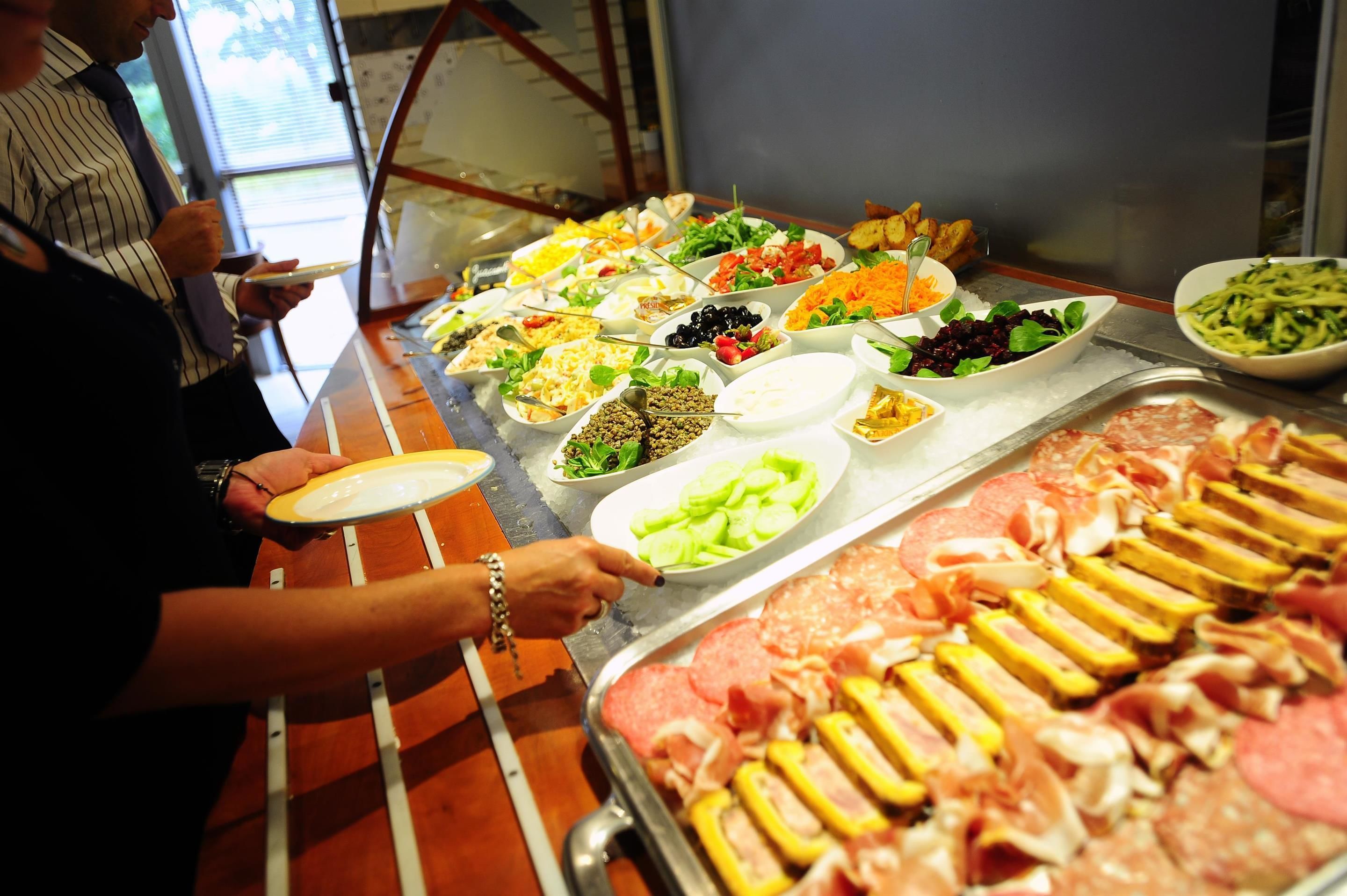 Un bufé con diversas opciones de comida, incluyendo carnes, ensaladas y verduras.