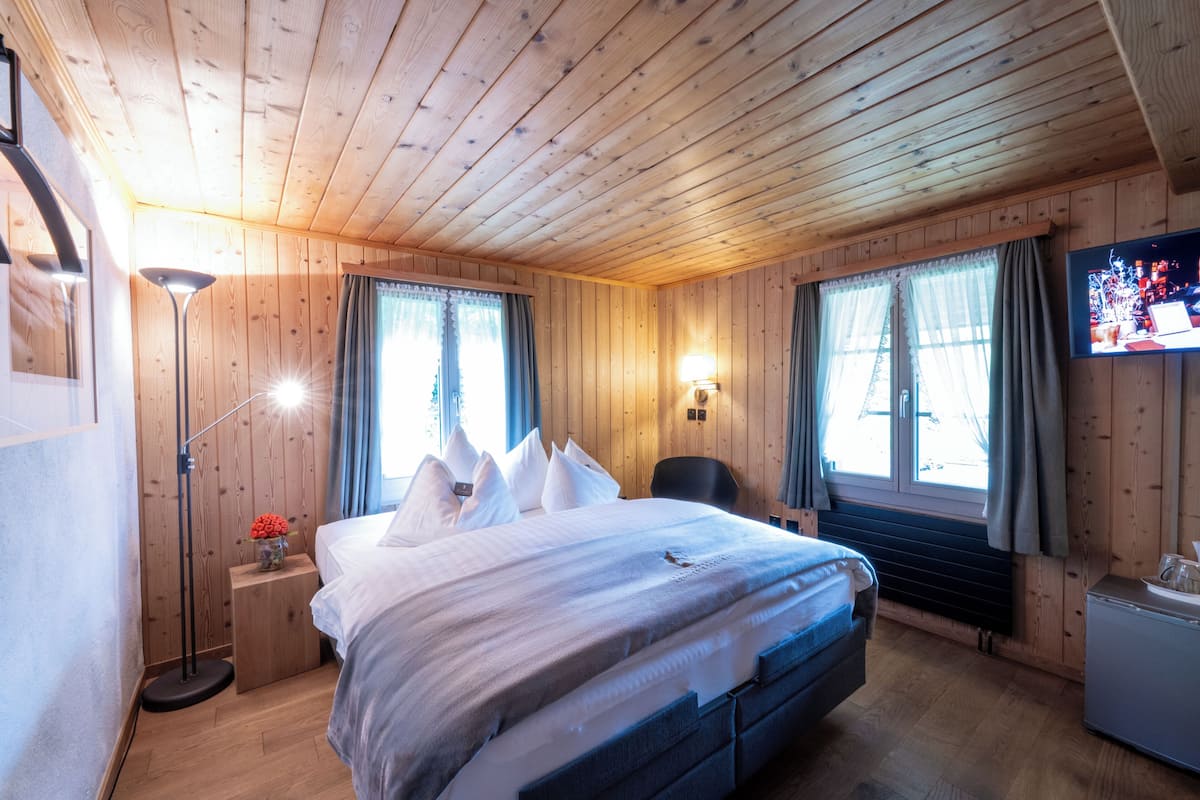 Ein Schlafzimmer mit Holzwänden, einem Bett, einer Nachttischlampe und einem Flachbildfernseher.