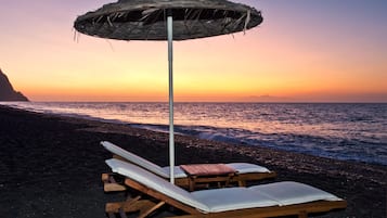 Accommodatie ligt op het strand, zwart zand, ligstoelen, parasols