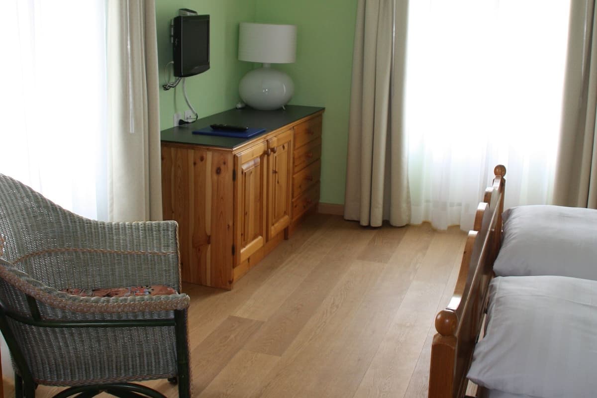 A room with a bed, a wooden cabinet, a television, and a chair.