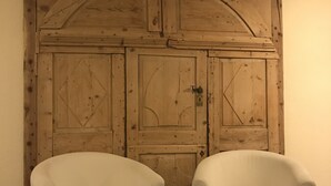 Two white armchairs in front of a wooden door with a rustic design.
