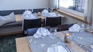 A dining area with tables set for two, a view of buildings outside, and a modern ceiling design.