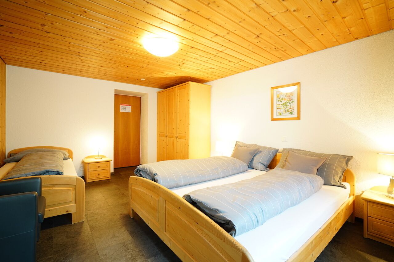 Quarto com duas camas, mobiliário de madeira e teto de madeira.