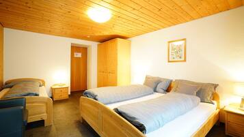 Quarto com duas camas, mobiliário de madeira e teto de madeira.