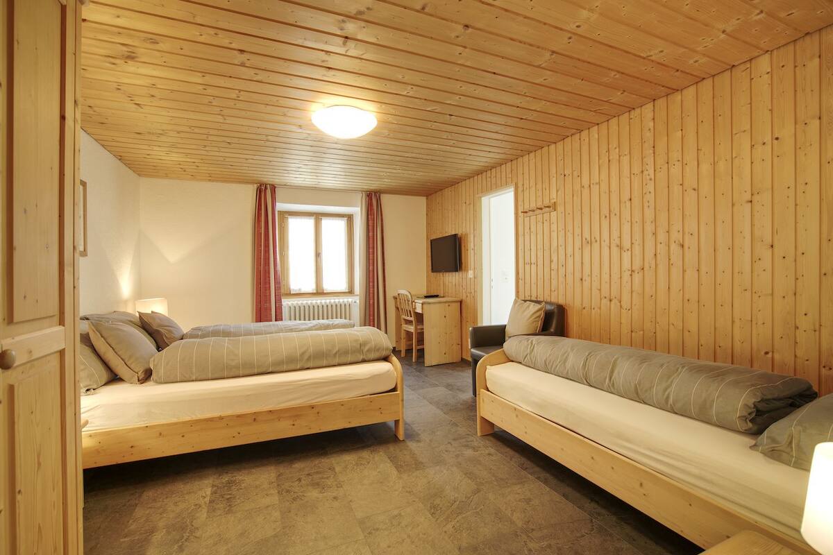 A cozy room with a bed, a sofa, a desk, and a television.