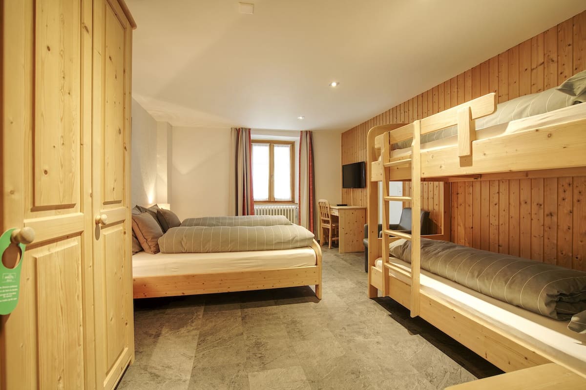 A room with bunk beds, a desk, and a television.