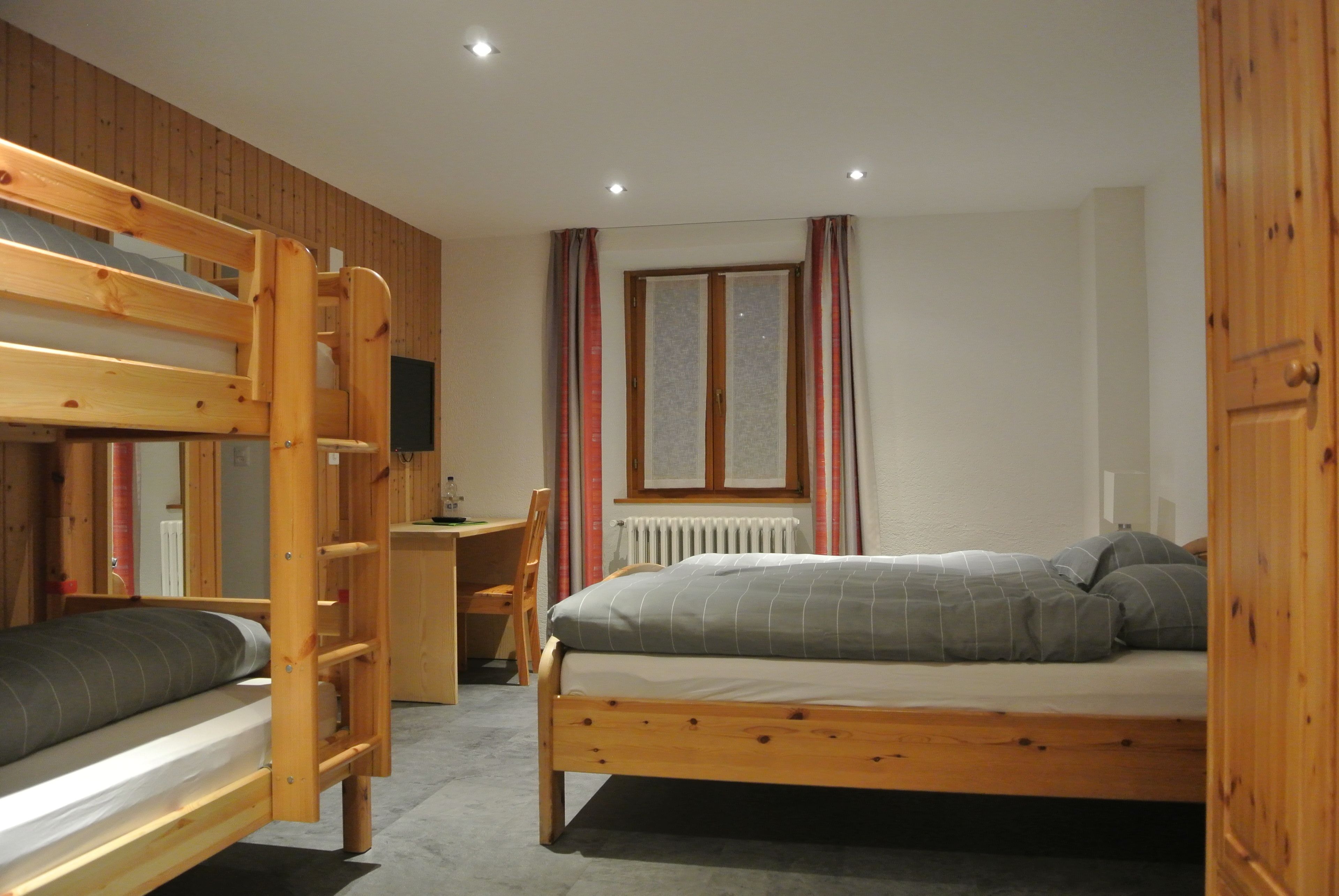 A room with a bunk bed, a desk, and a chair.