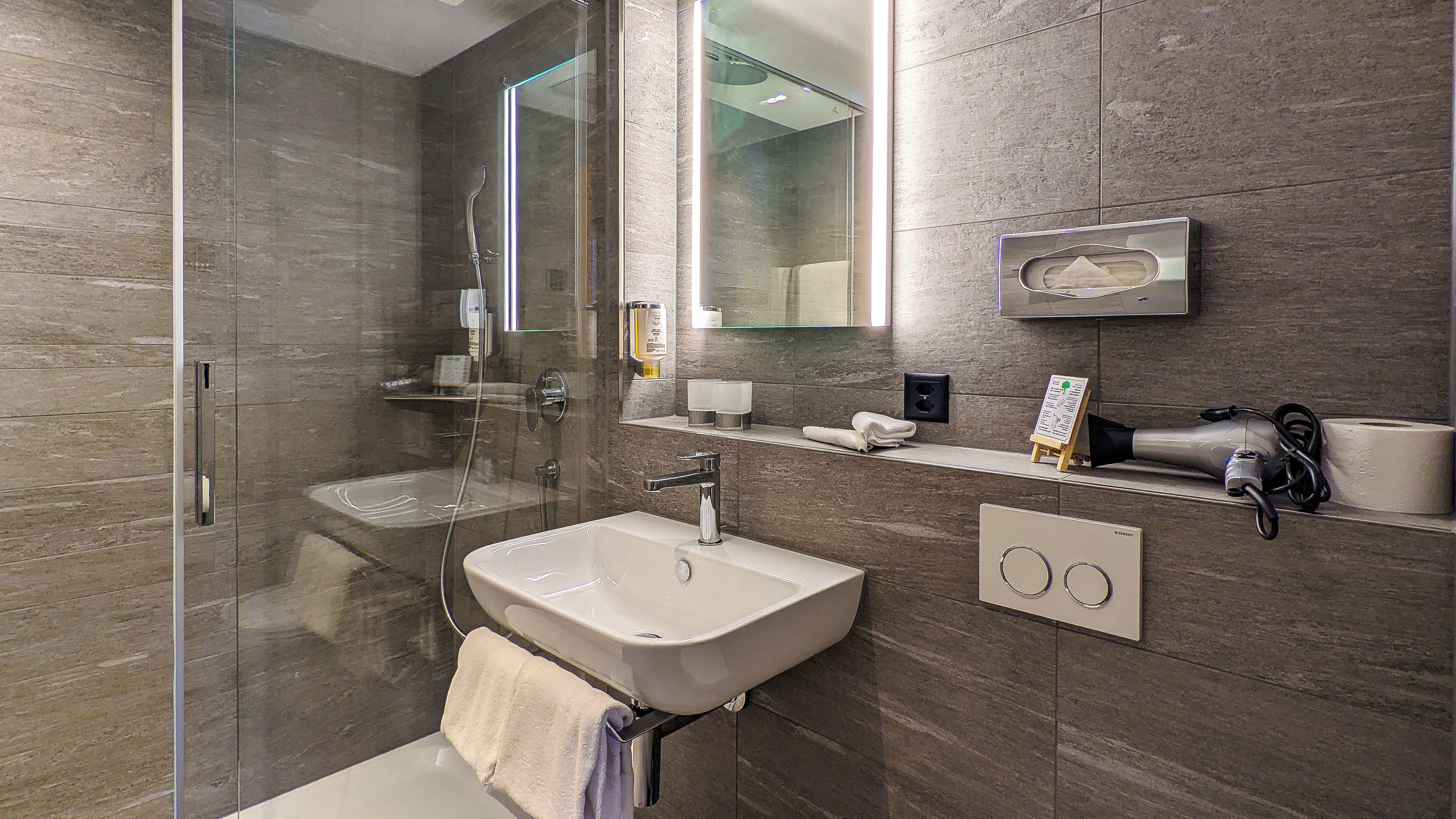 Un baño moderno con cabina de ducha de vidrio, un lavabo y un perchero para toallas.