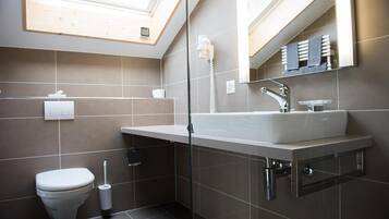 A modern bathroom with a skylight, a large sink, and a toilet.