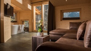 Una habitación acogedora con un sofá marrón, un televisor de pantalla plana en la pared y un ventanal con vistas al exterior.