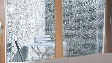 Ein Zimmer mit einer Glaskabine, einem Metalltisch und einem Stuhl.