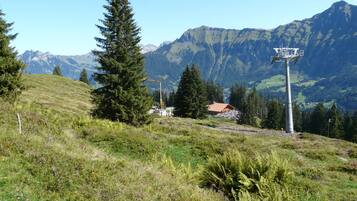 A mountain landscape with a ski lift, a building with a red roof, and a clear sky.