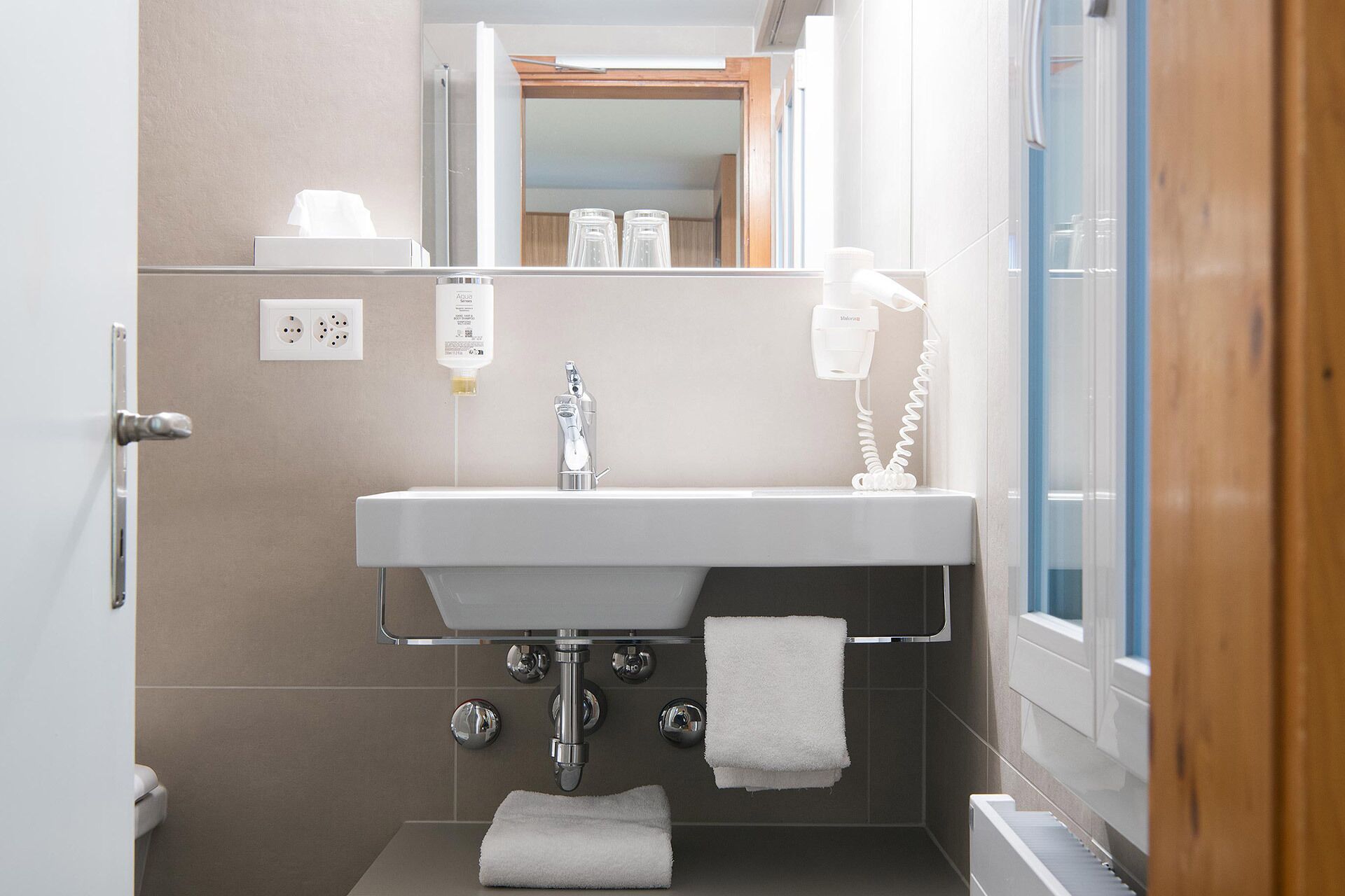 A bathroom with a sink, mirror, towel rack, and a hairdryer.