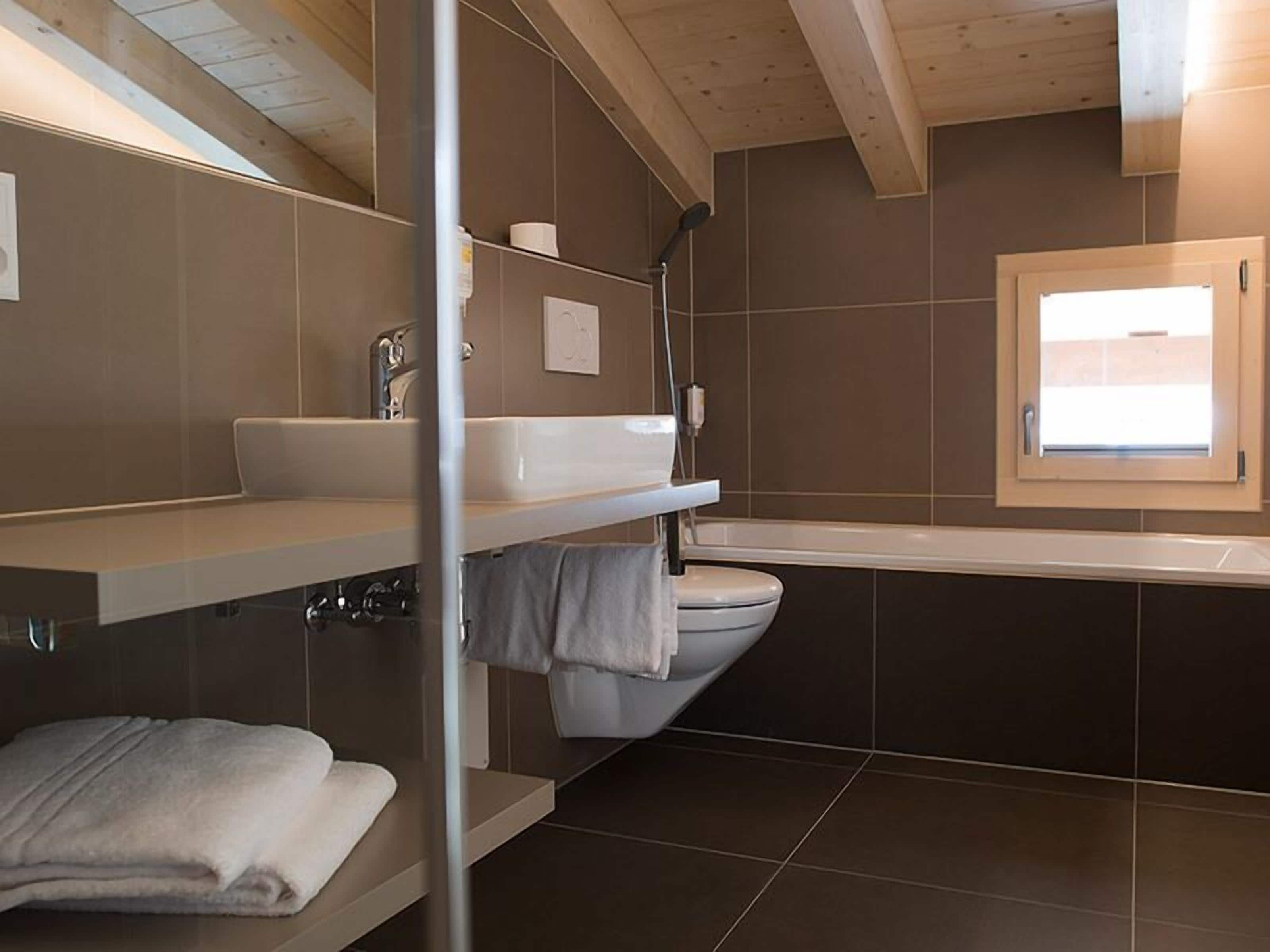 A modern bathroom with a bathtub, a toilet, and a sink.