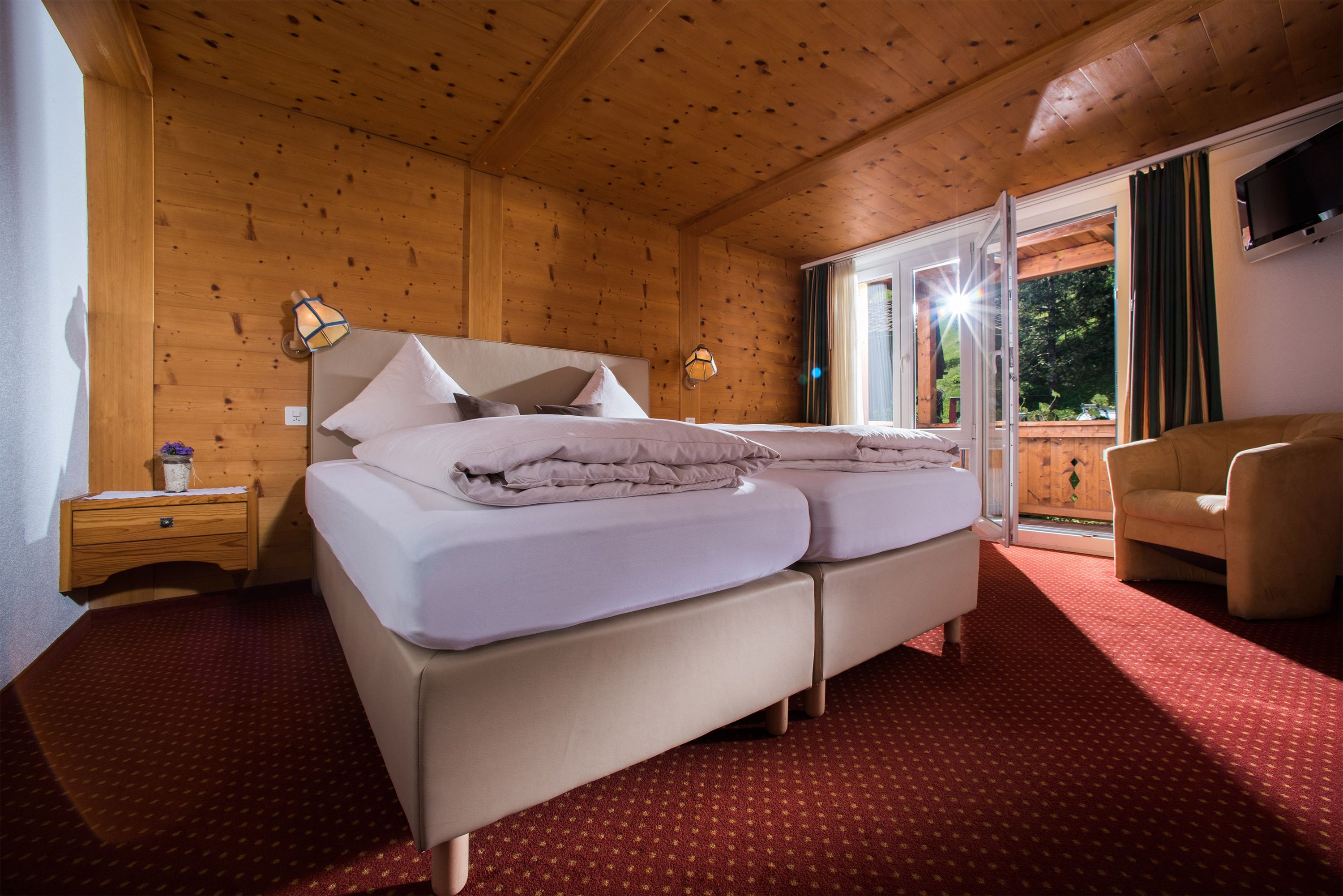 Une chambre aux murs lambrissés, avec un lit, une table de chevet et une chaise.